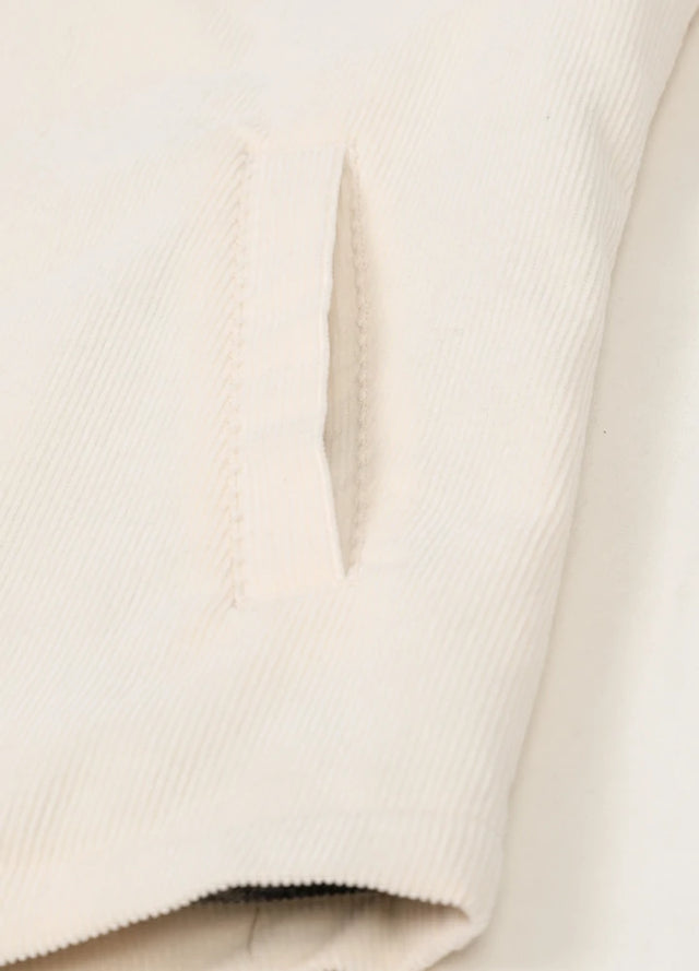 Close-up of the side hand pockets on a womens cream corduroy jacket