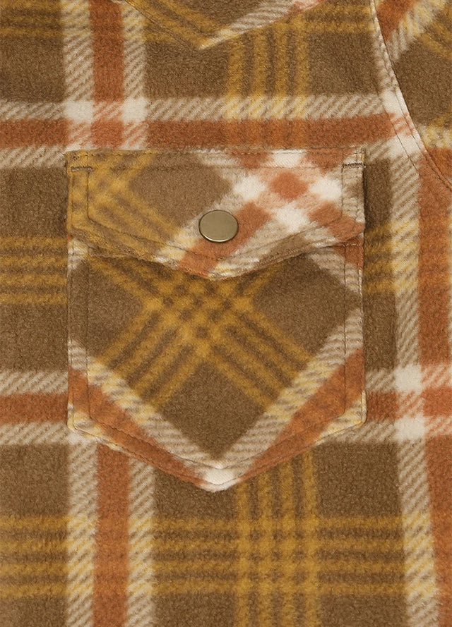 Close-up of a plaid fleece shirt pocket with a brown snap button, featuring a pattern of brown, orange, and cream.