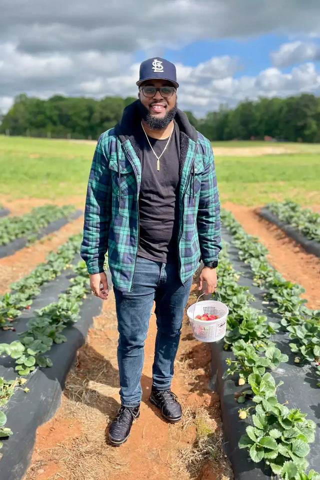 A man standing in a vegetable field in green navy winter sherpa lined flannel shirt jacket for men