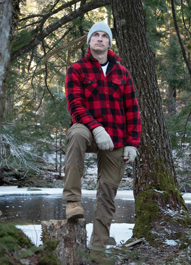 Front view of a man in a red men's button up jacket with sherpa lining is standing in front of a tree