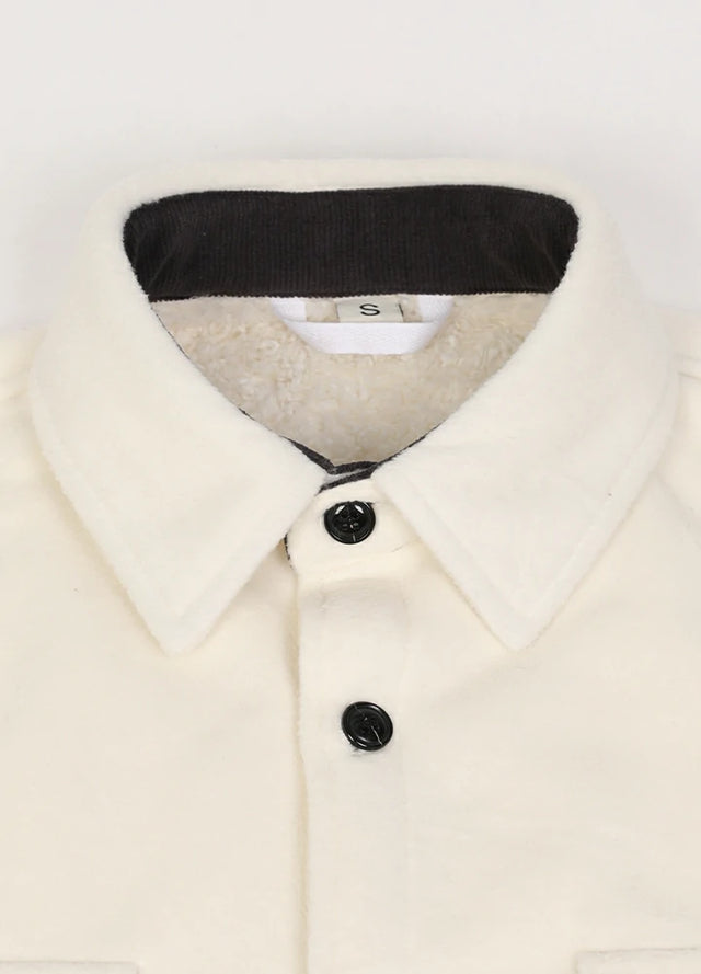 Close-up of the lapel of a solid white men's cozy button up fleece shirt jacket