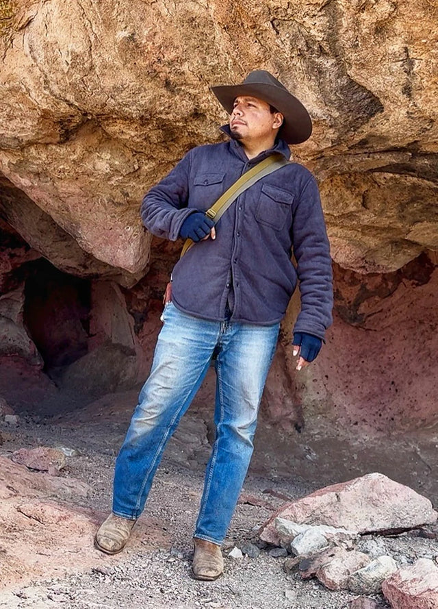 Front view of a man in a twill grey men's sherpa fleece lined shirt jacket carrying a crossbody bag