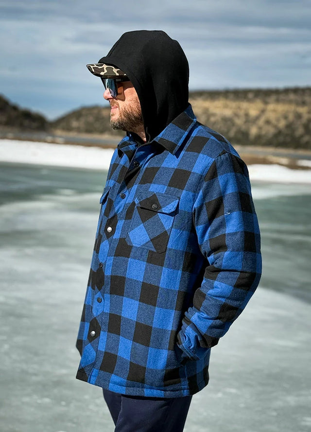 Side view of a man in blue and black men's quilted plaid flannel shacket standing on the ice