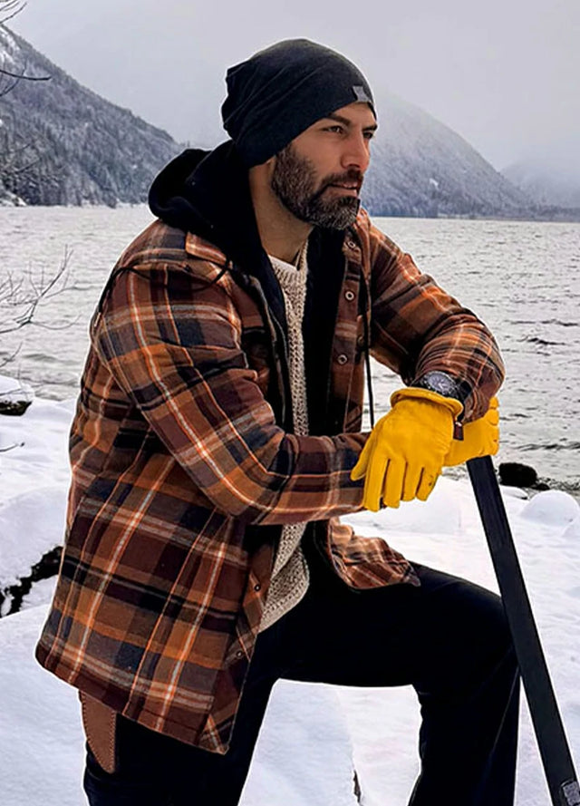 Side view of a man in a brown mens quilted lined flannel jacket holding an axe