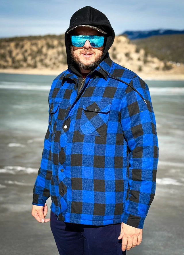 Front view of a man wearing a blue and black men's quilted plaid flannel jacket standing on the ice