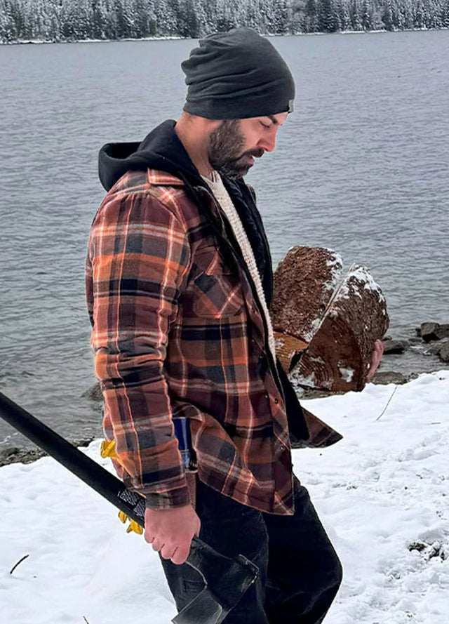 Side view of a man in a brown men's quilted lined flannel jacket holding firewood