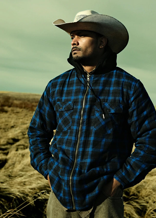 Front view of a man wearing a dark blue men's hooded flannel jacket leading his dog and looking to the side