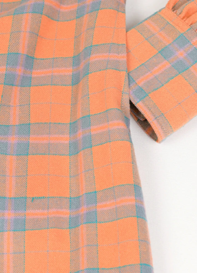 Close-up of women's pearl snap orange flannel shirt dress hand pocket