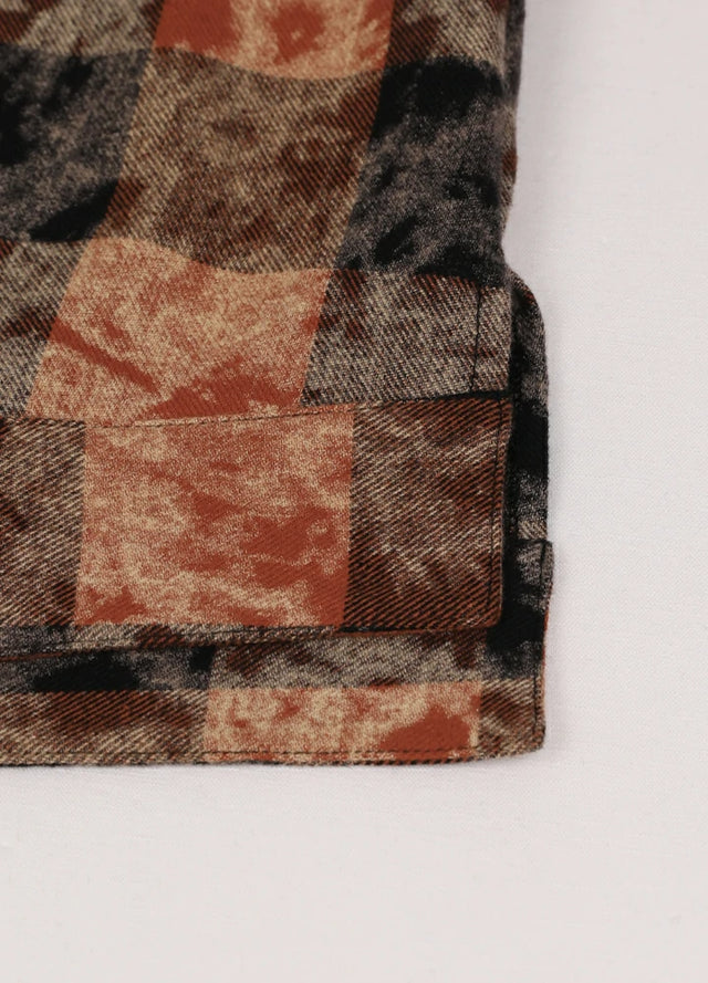 Close-up of the hem on a women's brown black long sleeve plaid shirt