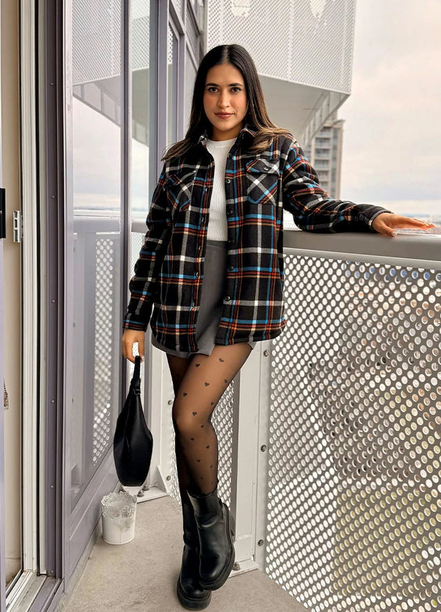 Women in a black sherpa lined fleece plaid shacket with button up