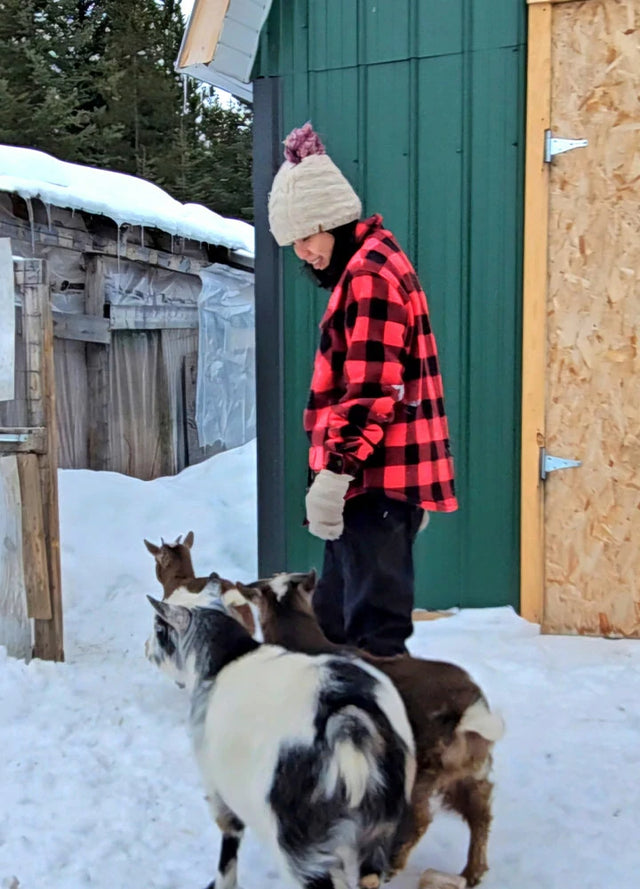 Side view of a woman in a sherpa-lined red plaid fleece jacket with a dog
