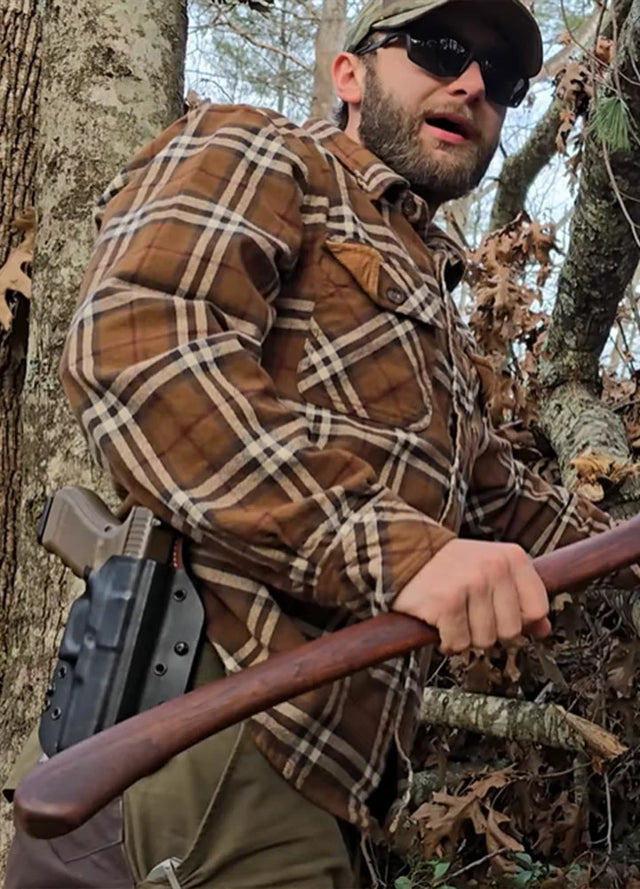 Side view of a man wearing a men's brown Timberline cotton flannel shirt holding an axe
