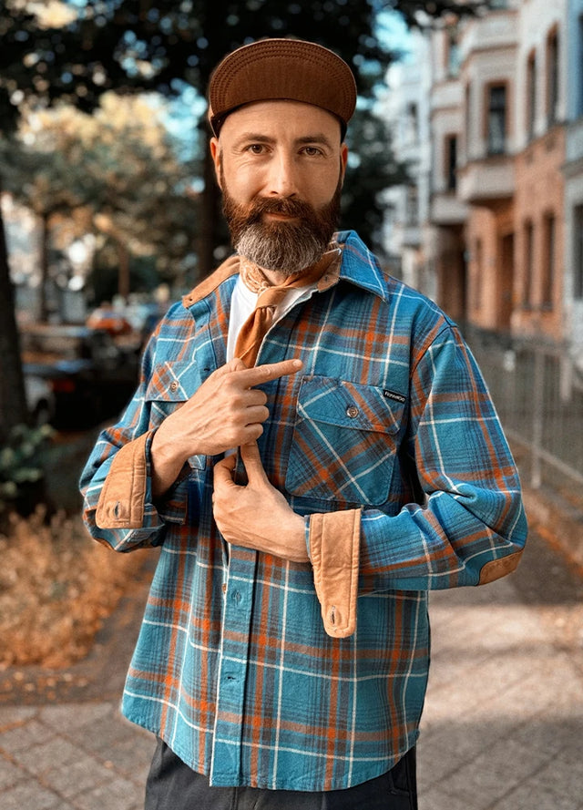 Front view of a man wearing a blue men's cozy plaid flannel shirt standing in the road
