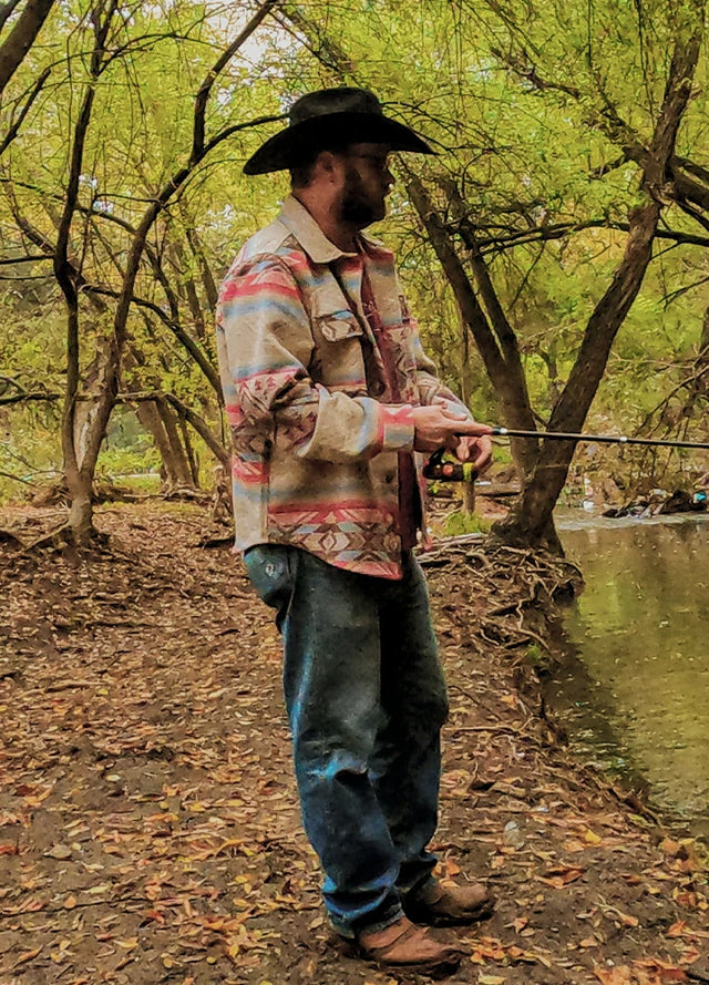 Side view of a man wearing a black and grey men's Aztec shirt jacket, standing sideways while fishing