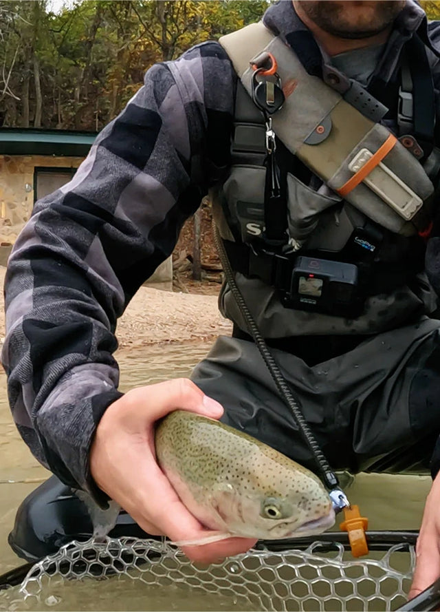 Front view of a man in a gray men's thick cotton checkered shirt holding a fish in his hands