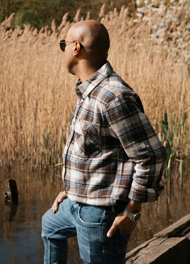 Side view of a man in a coffee white men's stalwart heavyweight cotton plaid shirt with one hand in the pocket