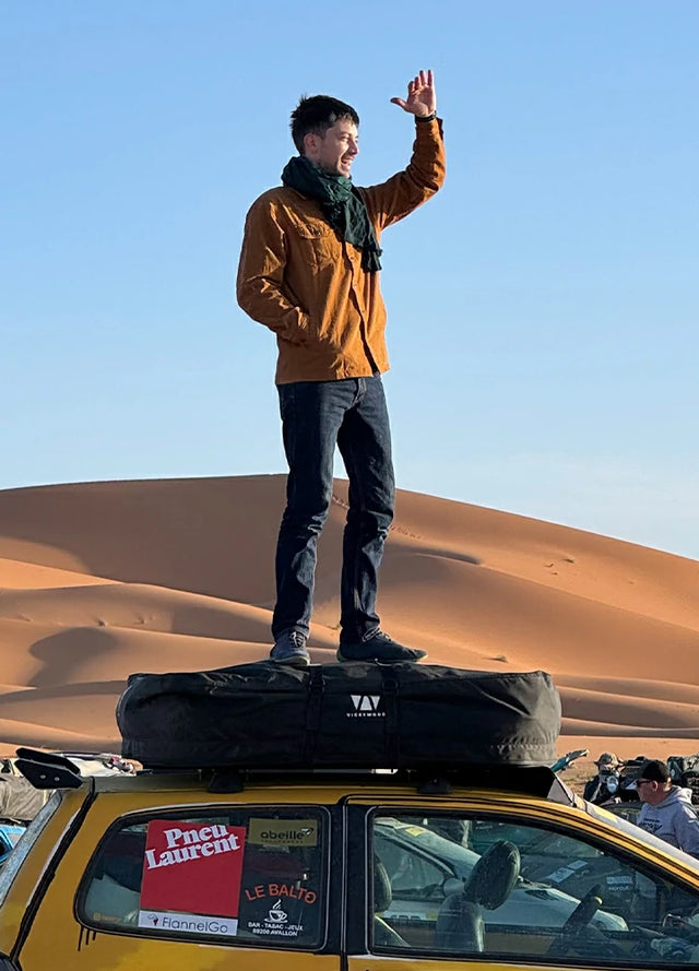 Front view of a man wearing a men's dark khaki flannel-lined heavy utility shirt jacket, standing on a vehicle and gazing into the distance