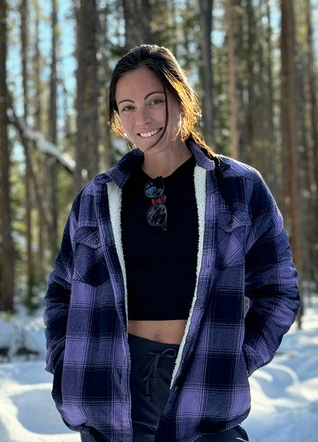 Women in a purple and black button down flannel shirt jacket with sherpa lining