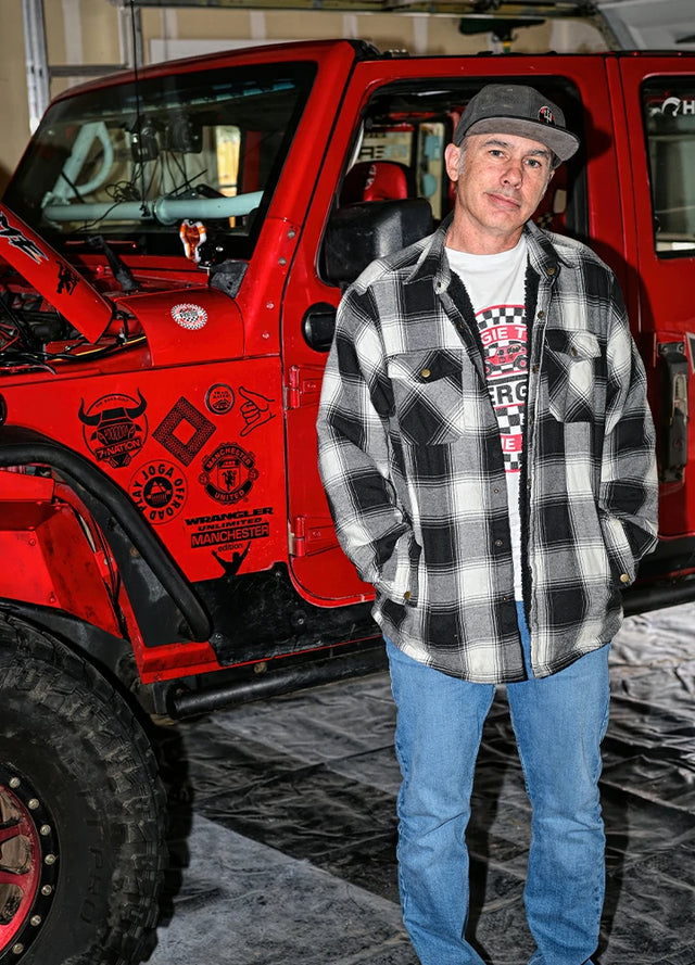 Front view of a man in a black white men's cozy snap button flannel shirt jacket with his hands in the pockets
