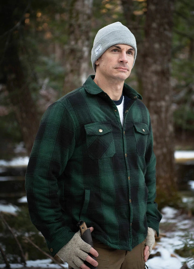 Front view of a man in a green black men's soft snap button flannel checked jacket standing in the snow
