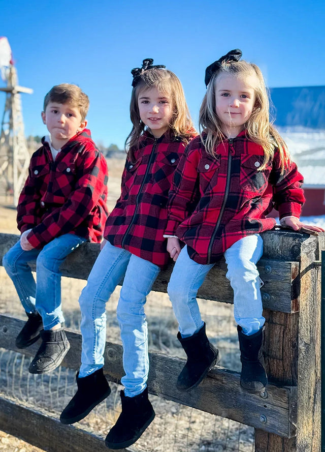 Children wearing red and black plaid flannel jackets sitting together enjoying the sunshine
