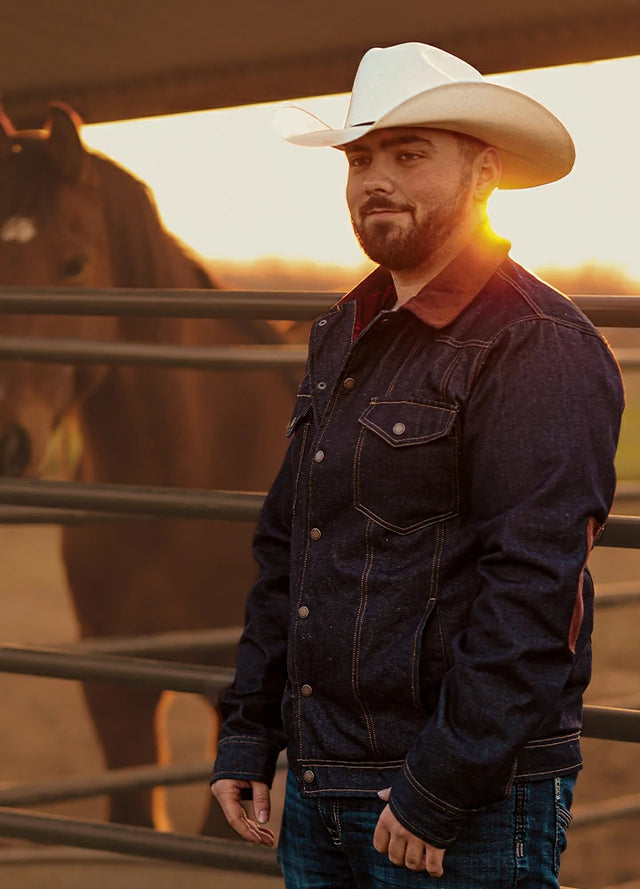 Front view of woman in a dark blue denim flannel men's shirt jacket leaning against the wall