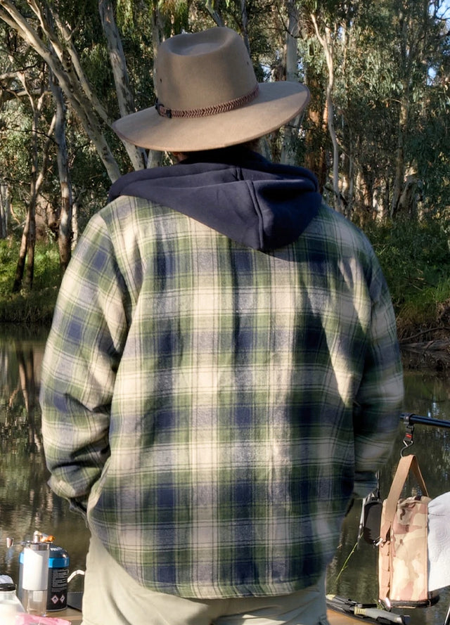 Back view of a man in a tea green men's flannel hooded jacket standing by a lake
