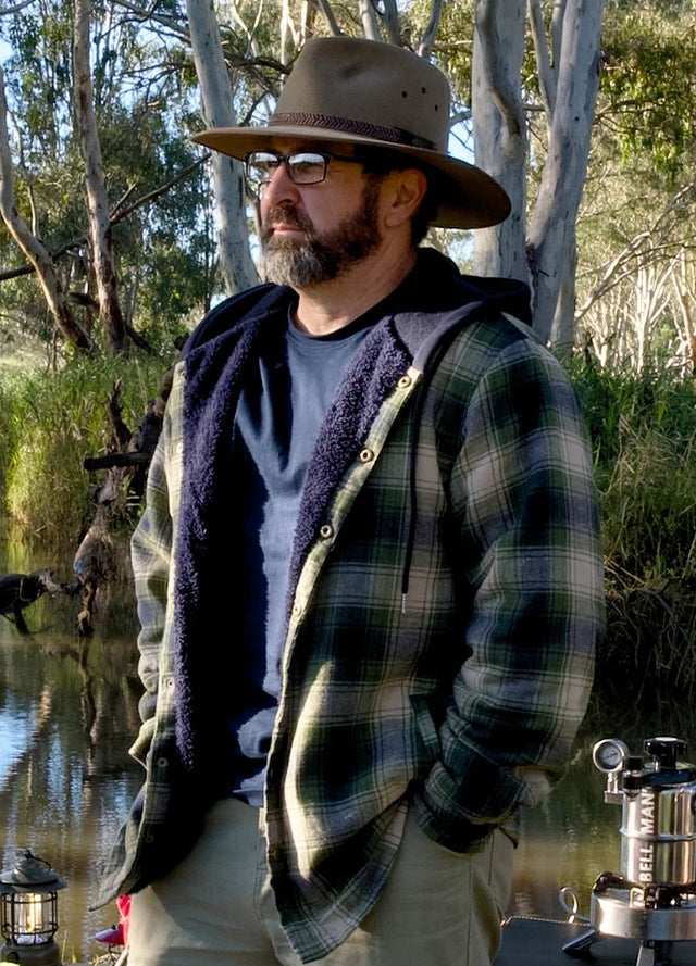 Side view of a man in a tea green men's hooded flannel jacket standing by a lake