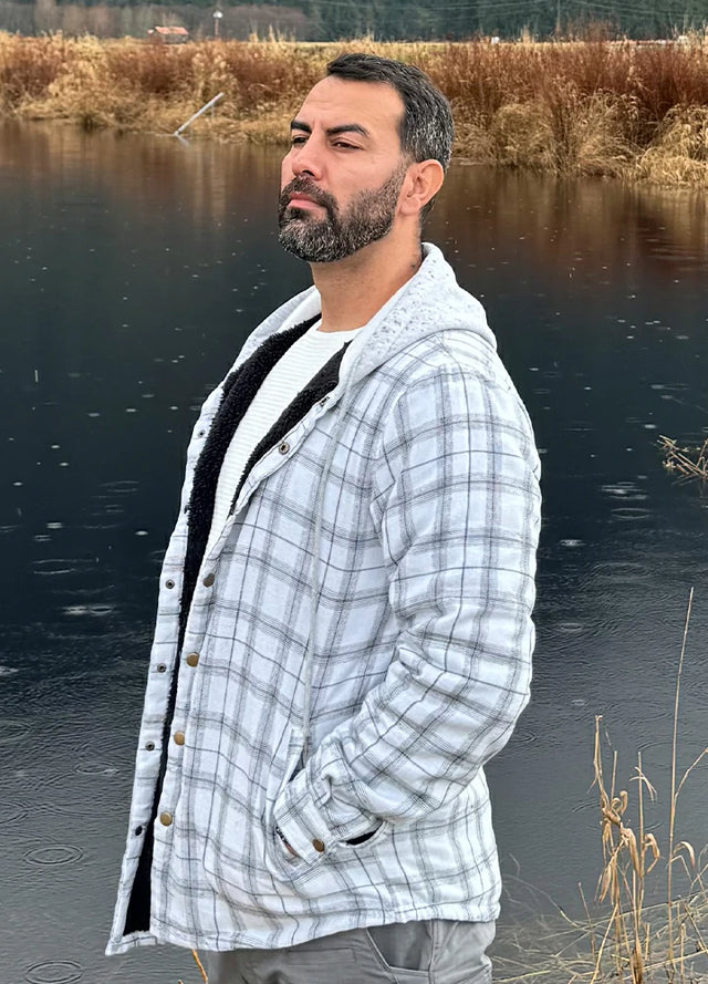 Front view of a man wearing white and gray men's flannel hooded jacket standing next to a pond