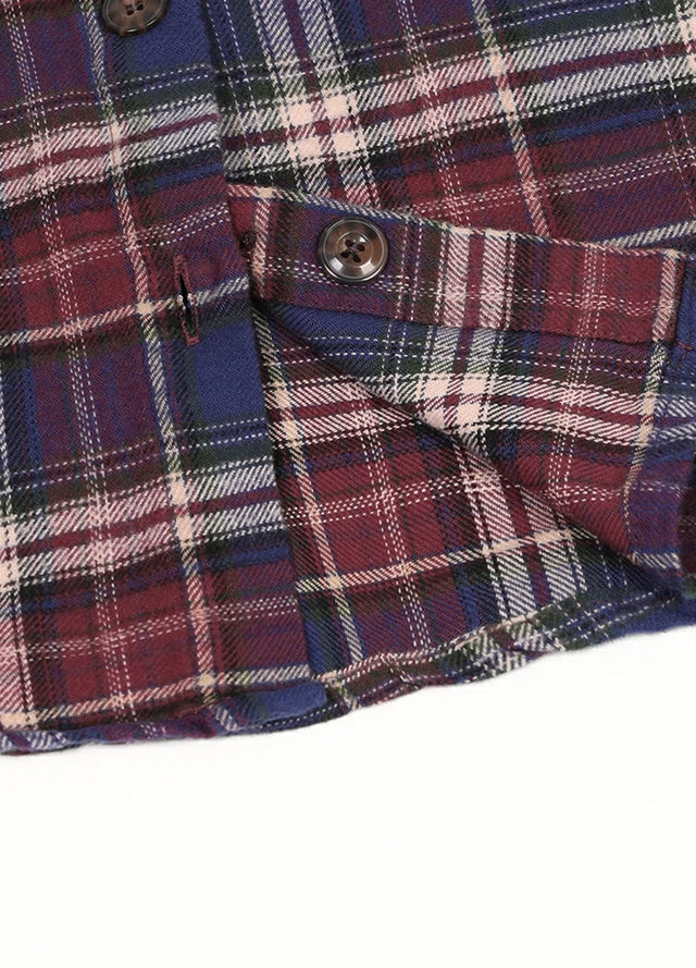 Detailed view of burgundy plaid flannel shirt button and fabric