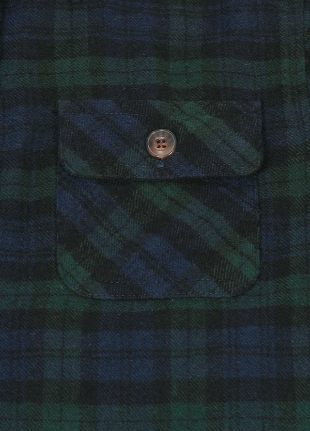 Zoomed-in view of men's dark green plaid flannel shirt chest pockets
