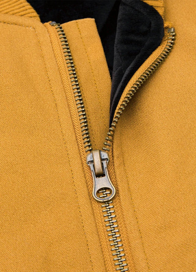 Close-up of the durable brass zipper on men's yellow arctic quilted lined canvas work vest