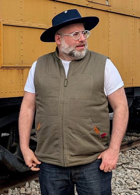 Front view of a man in a army green men's quilted lined washed outdoor vest