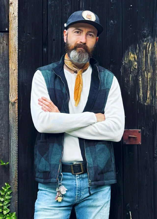 Front view of a man in a warm black green plaid men's reversible vest fold his arms across your chest