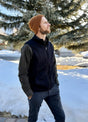 Side view of a man wearing a black men's fleece sweater vest standing in the snow