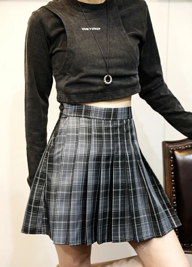 A woman in a high-waisted black and gray plaid pleated mini skirt