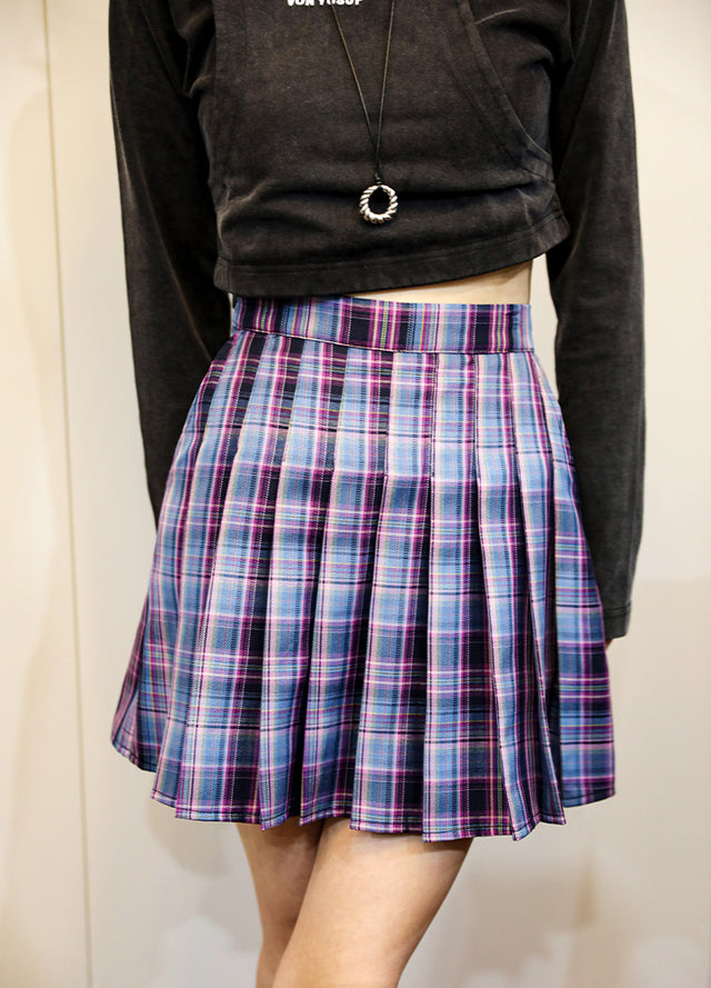 A woman in a high-waisted purple blue plaid pleated mini skirt