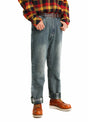 A man wearing flannel-lined straight-leg jeans, standing sideways with his hands in his pockets