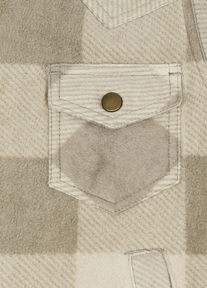 Close-up of a beige and off-white plaid fabric with a front pocket featuring a single round brass snap button.