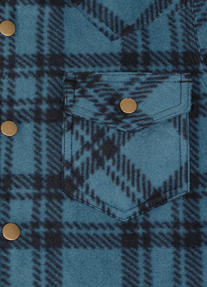 Close-up of a blue and black plaid button-up shirt with a chest pocket and brass snap buttons.