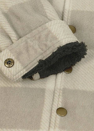 Close-up of a cream-colored textured jacket with a dark gray sherpa lining visible at the cuff, featuring brass snap buttons.