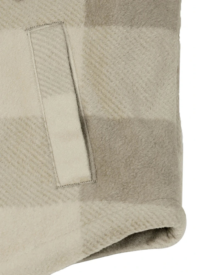 Close-up of a soft woven textile with a plaid pattern in warm beige and light taupe tones, showing a folded edge and stitched detail.