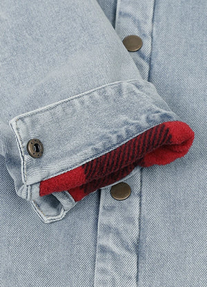 Close-up of a light blue denim jacket with a folded cuff showing a red and black buffalo plaid lining.