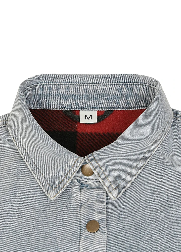 Close-up of a light-wash denim shirt collar with a red and black plaid lining and a white size label marked 'M'.