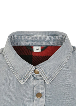 Close-up of a light-wash denim shirt collar with a red and black plaid lining and a white size label marked 'M'.