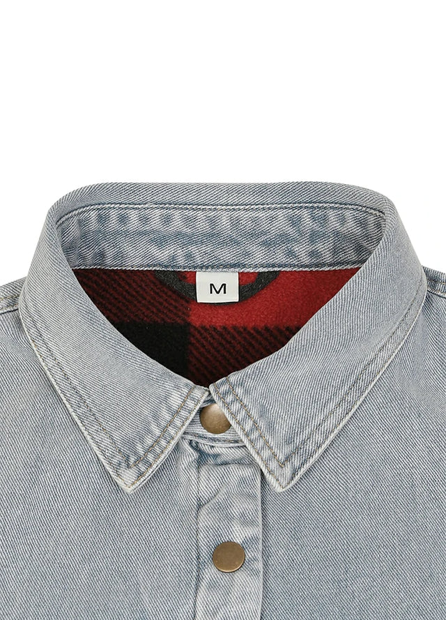 Close-up of a light-wash denim shirt collar with a red and black plaid lining and a white size label marked 'M'.
