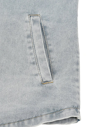 Close-up of a light blue denim fabric with a vertical welt pocket and visible stitching.