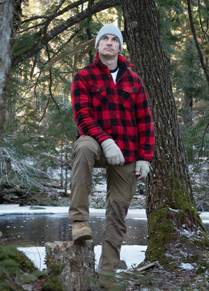 Front view of a man in a red men's button up jacket with sherpa lining is standing in front of a tree