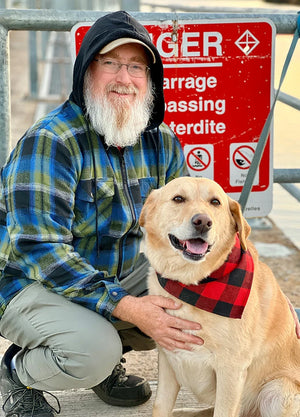 Front view of a man in green blue men's sherpa lined flannel jacket with a hood holding a dog
