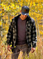 Front view of a man in a gray men's sherpa lined flannel shacket standing in the woods